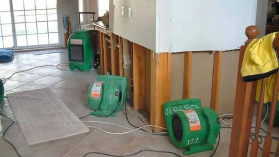Opened wall cavity with green air movers drying the area before repairs